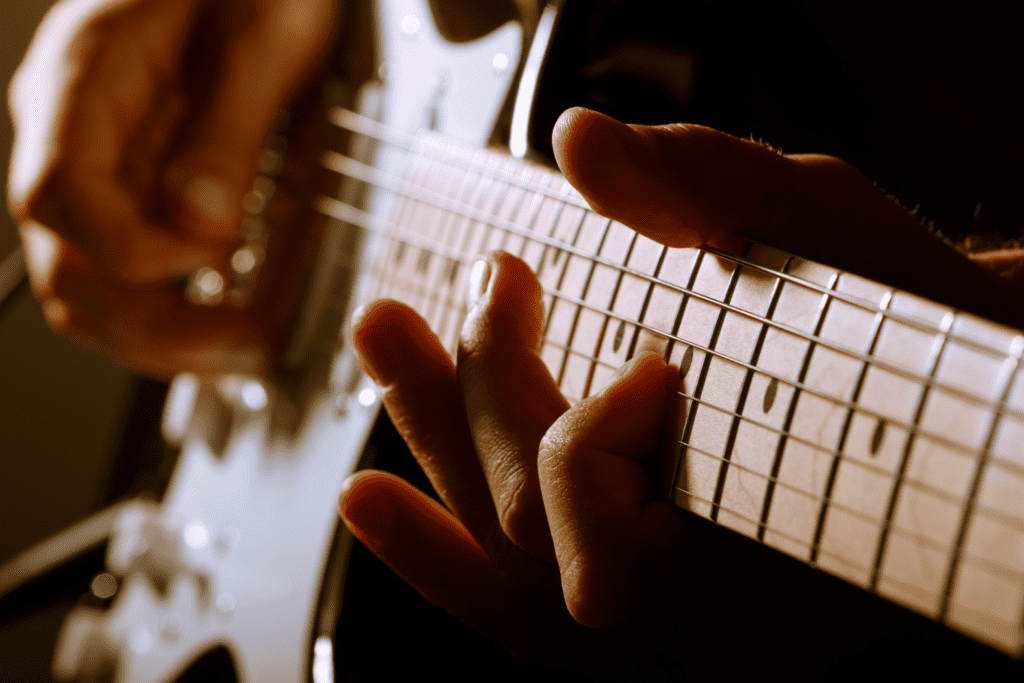 man playing an electric guitar, displaying coordination between the fretting and picking hand - required for sweeping