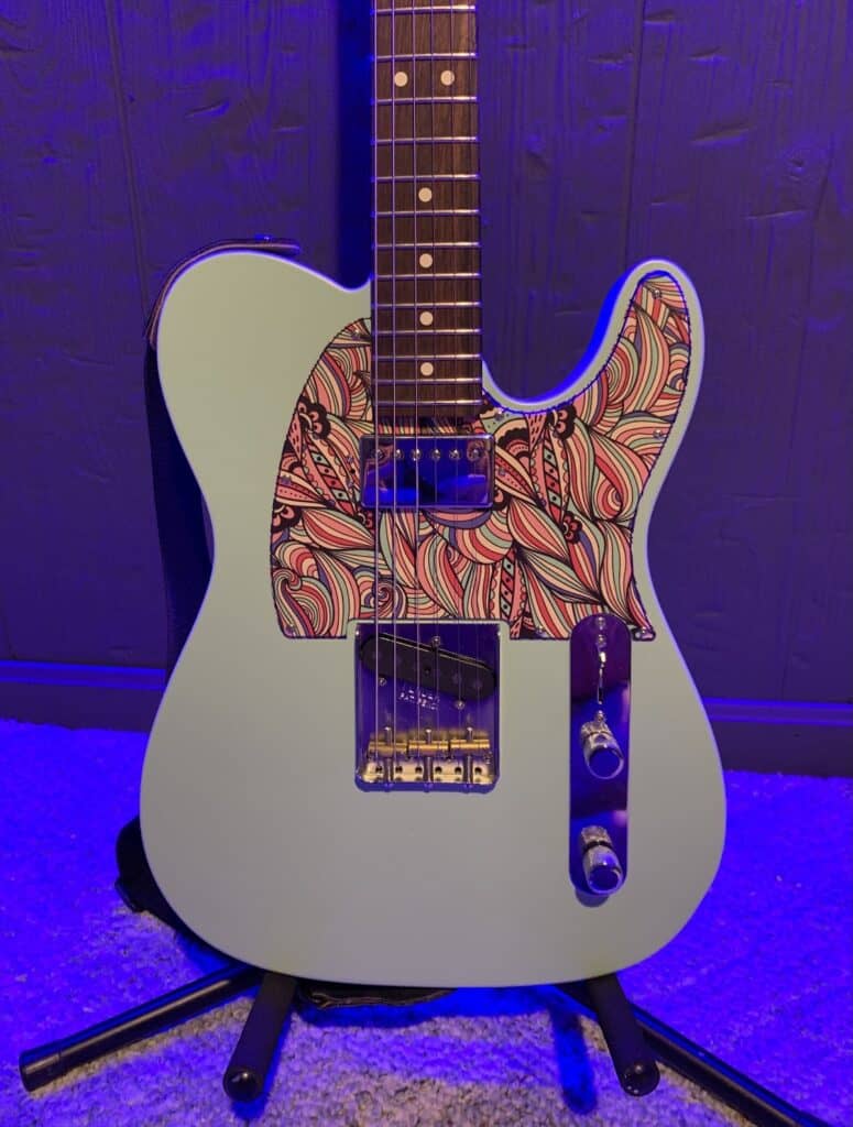 a tele style guitar with a custom pickguard