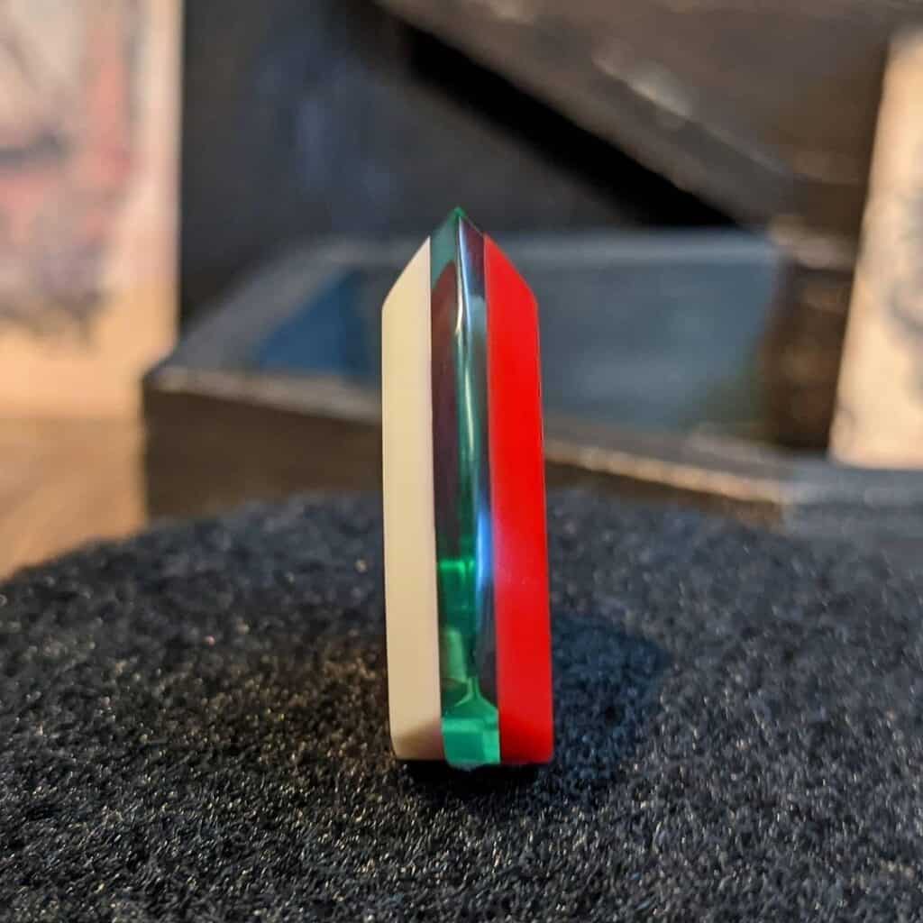 a thick white, green, and red northernghost plectrum from the side