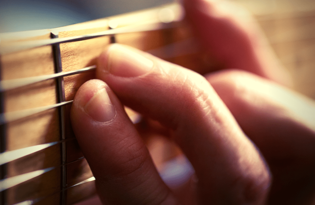 Guitar player played an F chord on an electric guitar with unfinished maple fretboard