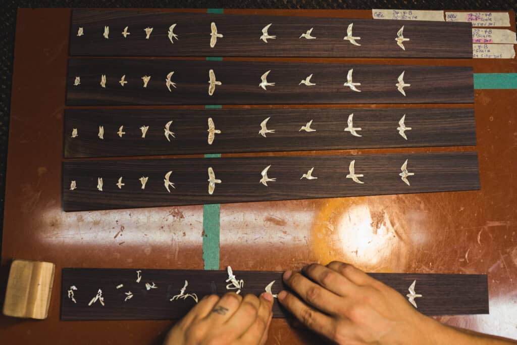 A PRS Employee Placing Inlays On A Guitar Fretboard