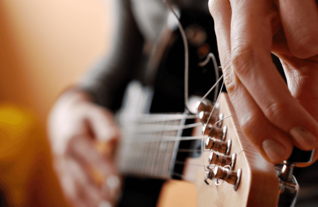 a young guitar player making sure that their guitar is still in pitch after tuning all of the strings to open A tuning