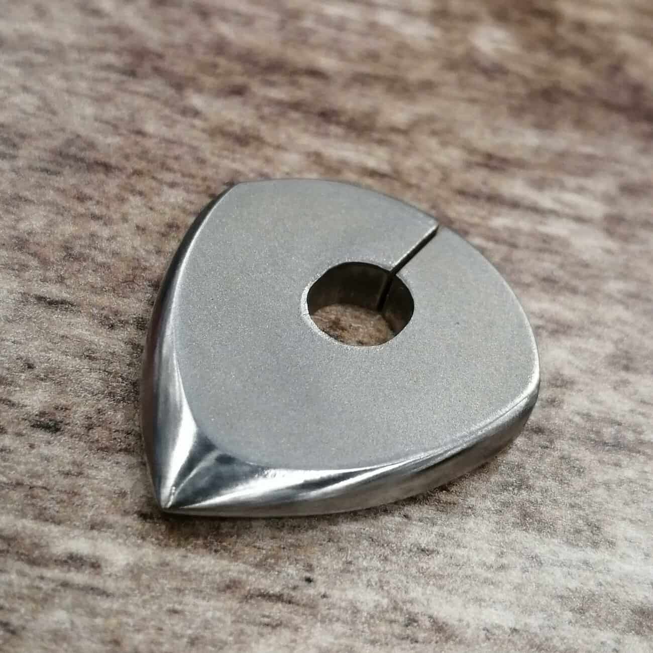 a thick titanium pick by ohm picks