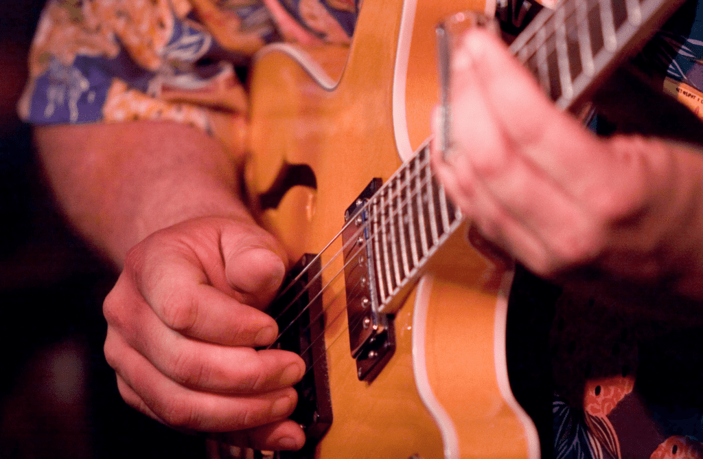A guitar player is playing a slide on a guitar tuned to open a tuning