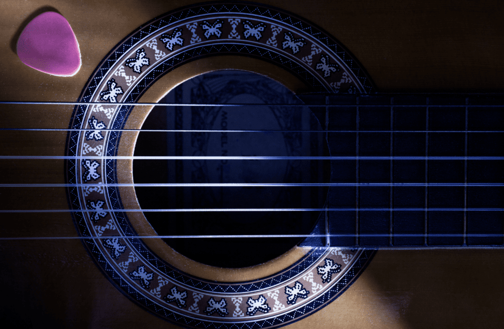 A Guitar Pick Next To A Guitar's Sound Hole