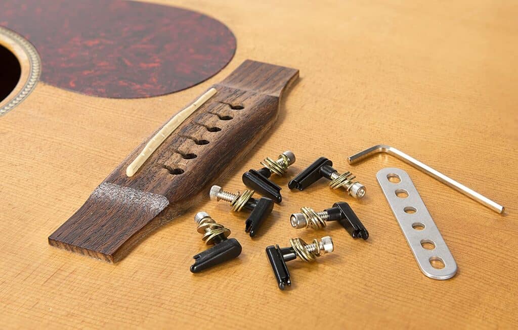Everything included with power pins 2.0 arranged on an acoustic guitar. An Allen wrench, metal plate, 6 power pins, washers and screws.