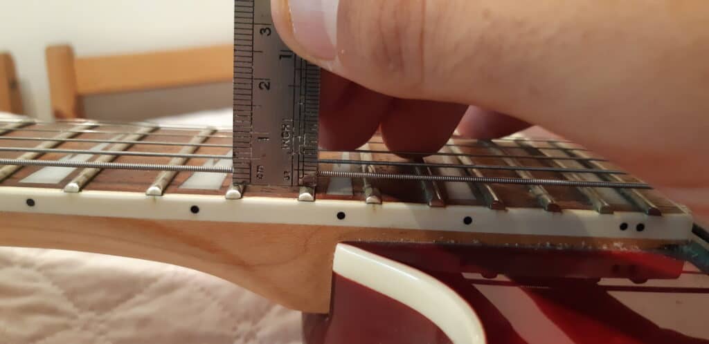 Measuring the action of the low E string while setting up a guitar