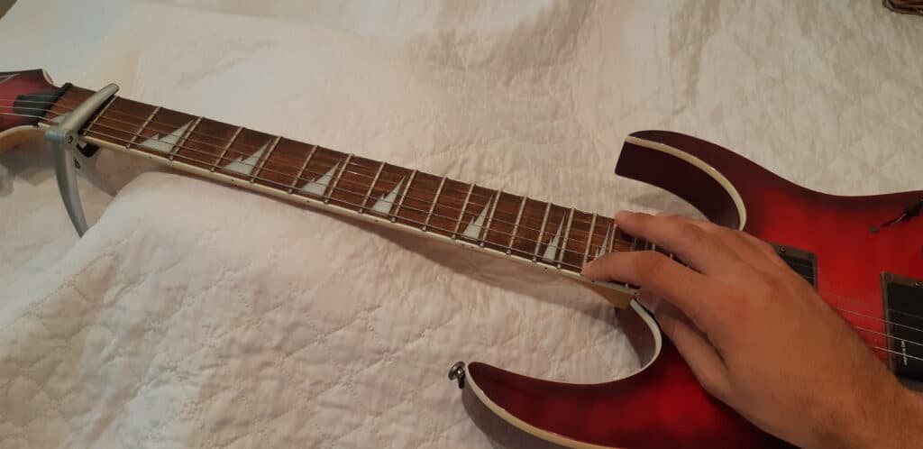 Performing a tap test to help determing the neck curvature as a part of a guitar set up