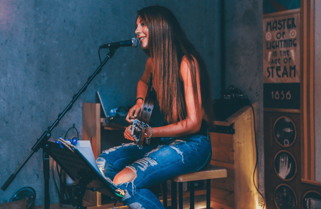 A Girl Sings and Plays The Guitar at The Same Time