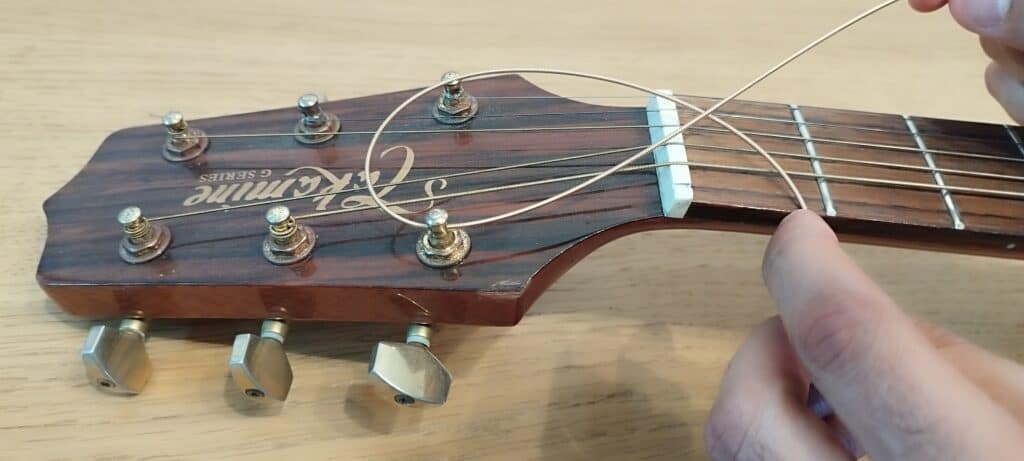 Make a loop by moving the excess part of the string toward the middle of the headstock and below the part connected to the bridge