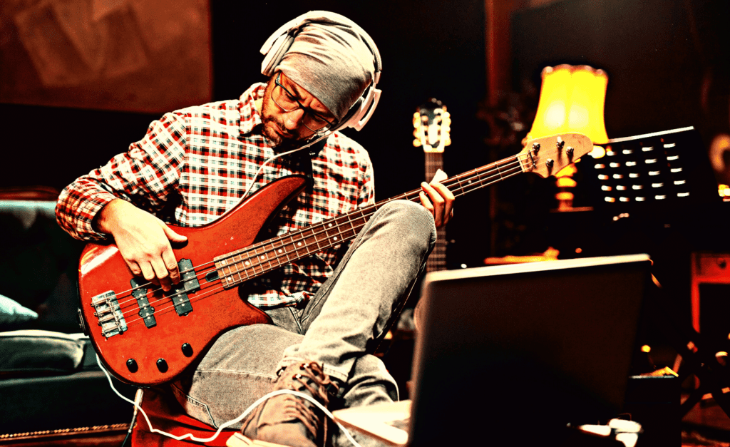 A bass player recording a bass guitar at his home studio