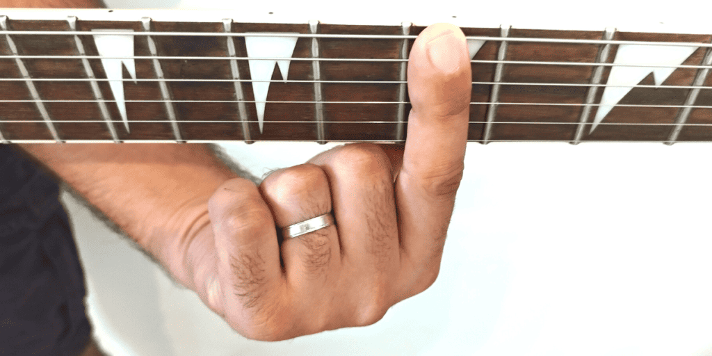 Utilize the flat part on the side of your index finger rather than holding it facing the strings