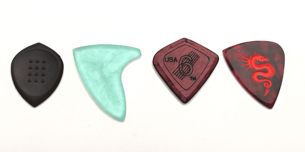 Four picks that have both narrow and wide tips: Acoustic Attak's Stealth, a Mako pick, SixStringers' Wild Plectrum, and Smaug by Osiris Accessories