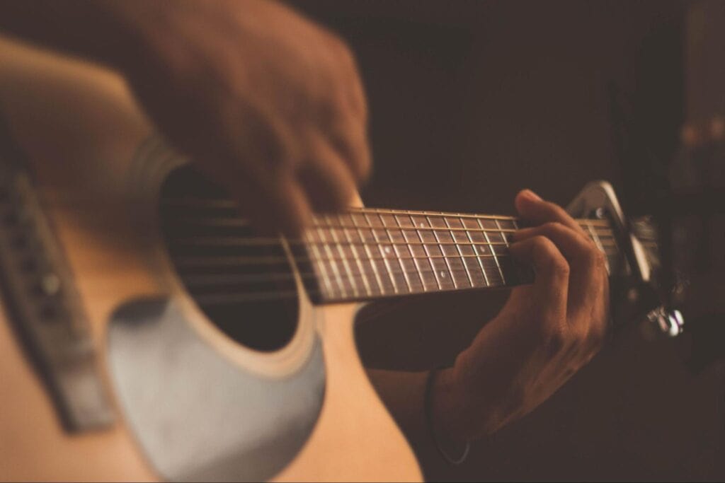 A beginner guitar player strums an acoustic guitar