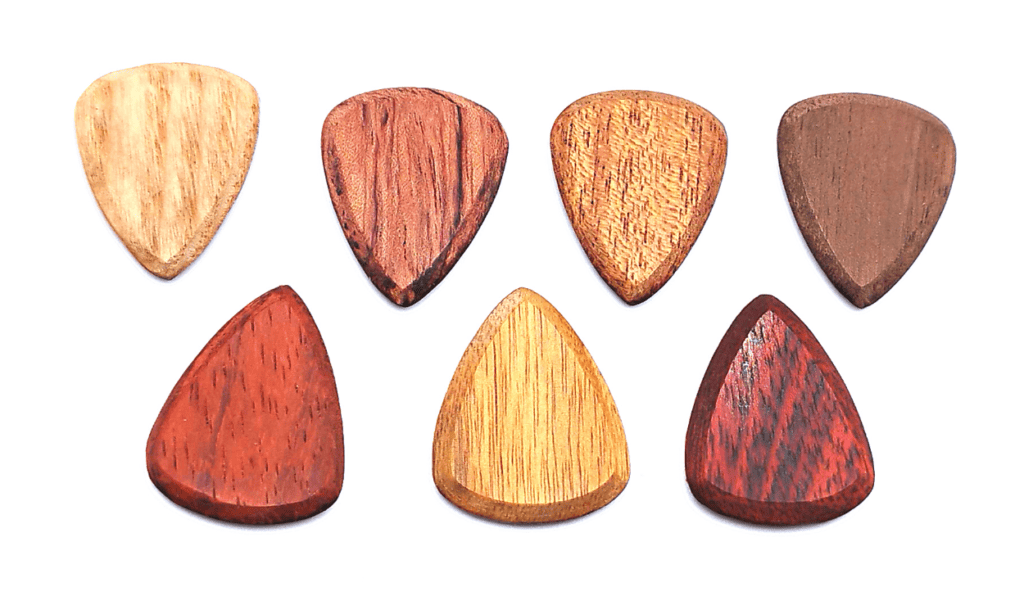 Wooden guitar picks made by SixStringers, from left to right_ Ash, Bloodwood, Bubinga, Canarywood, Light Mahogany, Padauk, and Walnut